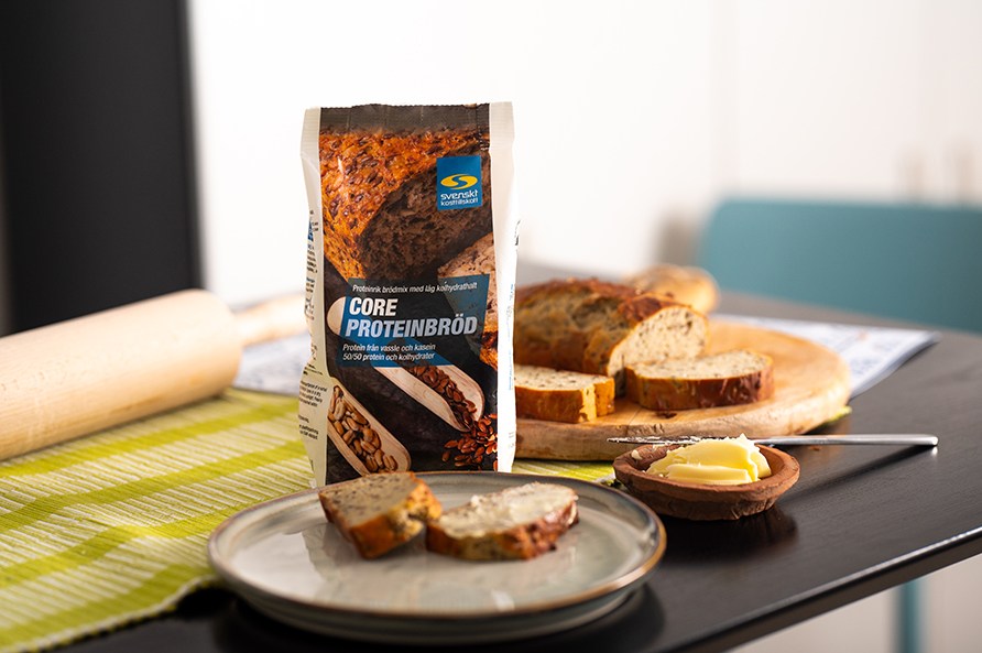 Et bagt proteinbrd ligger klar til at spises ved siden af Core Proteinbrd posen. 